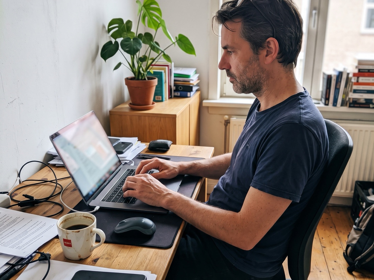 Man werkt geconcentreerd aan zijn laptop in een klein thuiskantoor