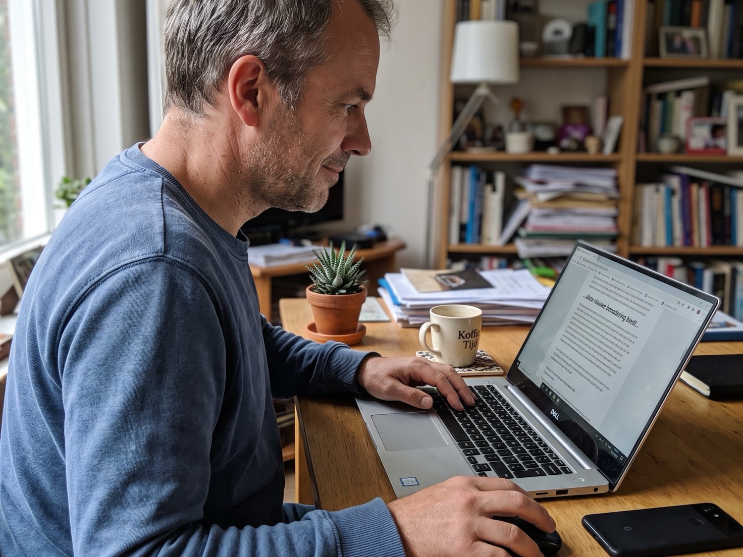 Adviseur werkt over de schouder gezien aan een laptop op een bureau, bezig met een social media post