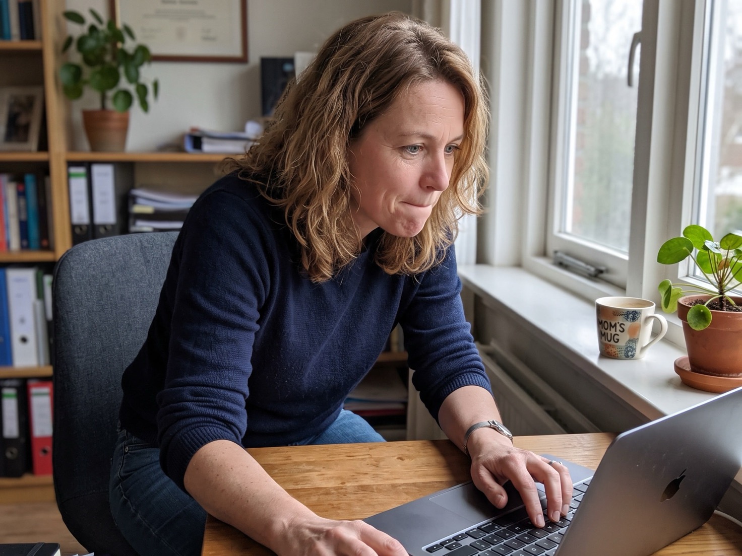 Zelfstandig ondernemer werkt geconcentreerd aan haar laptop in haar praktijkruimte