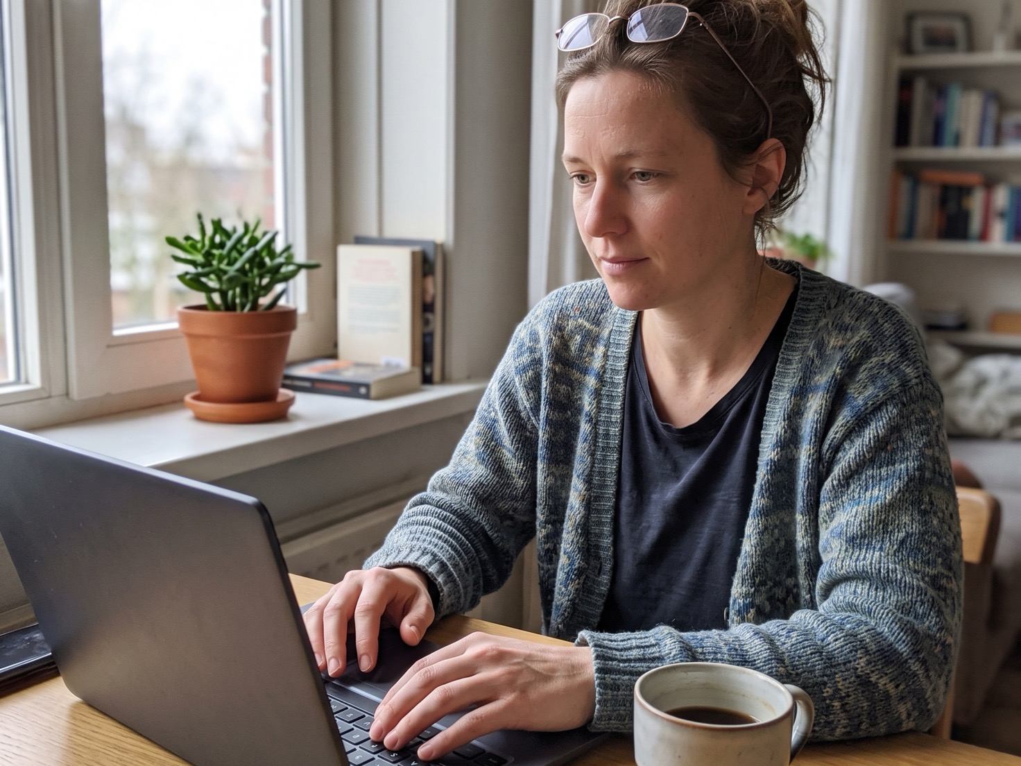 Ondernemer werkt geconcentreerd achter haar laptop aan tafel bij het raam