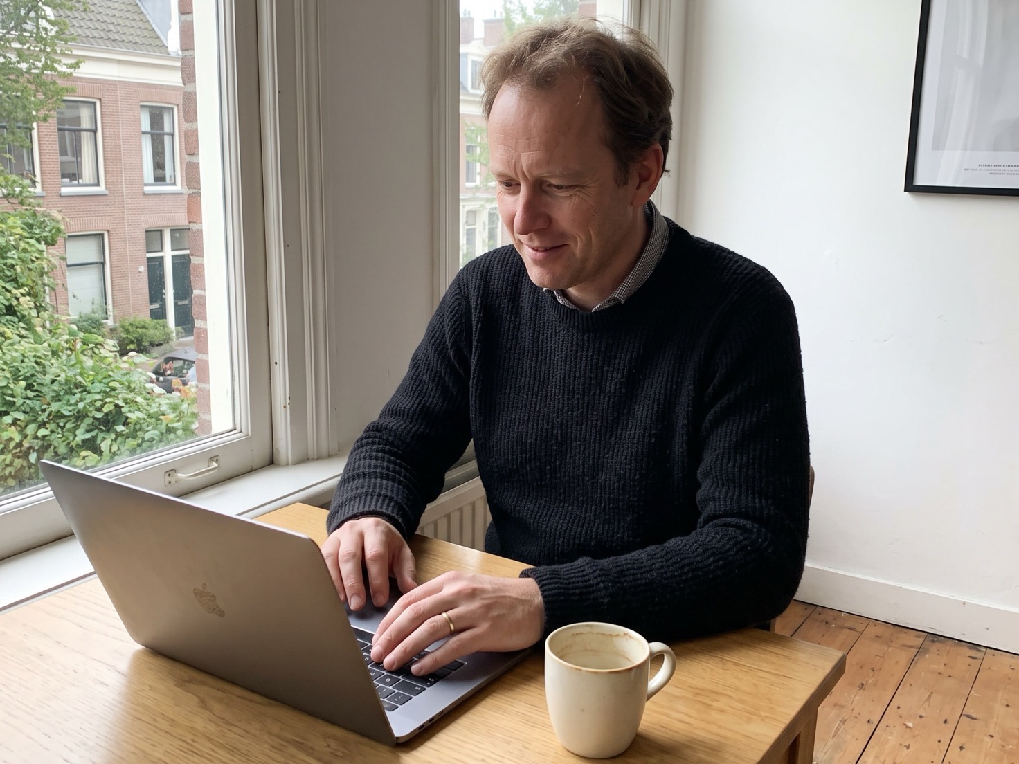 Solo-ondernemer werkt geconcentreerd aan tafel bij het raam