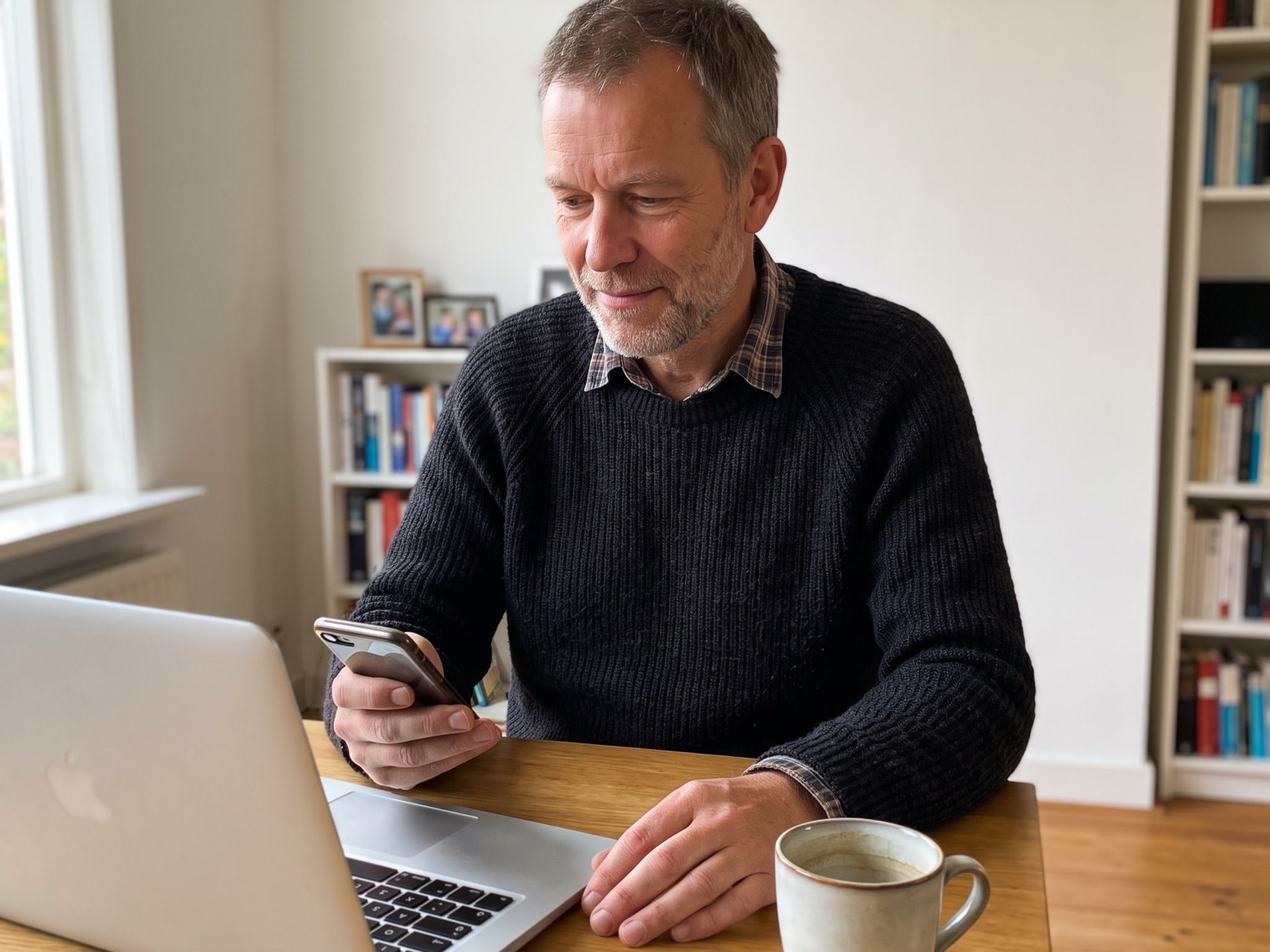 Man leest een reactie op zijn telefoon aan zijn werktafel