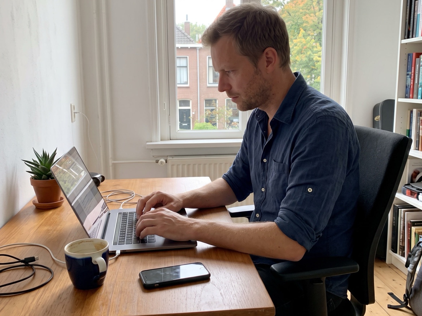 Zzp'er werkt geconcentreerd achter zijn laptop om zijn nieuwsbrief in te korten