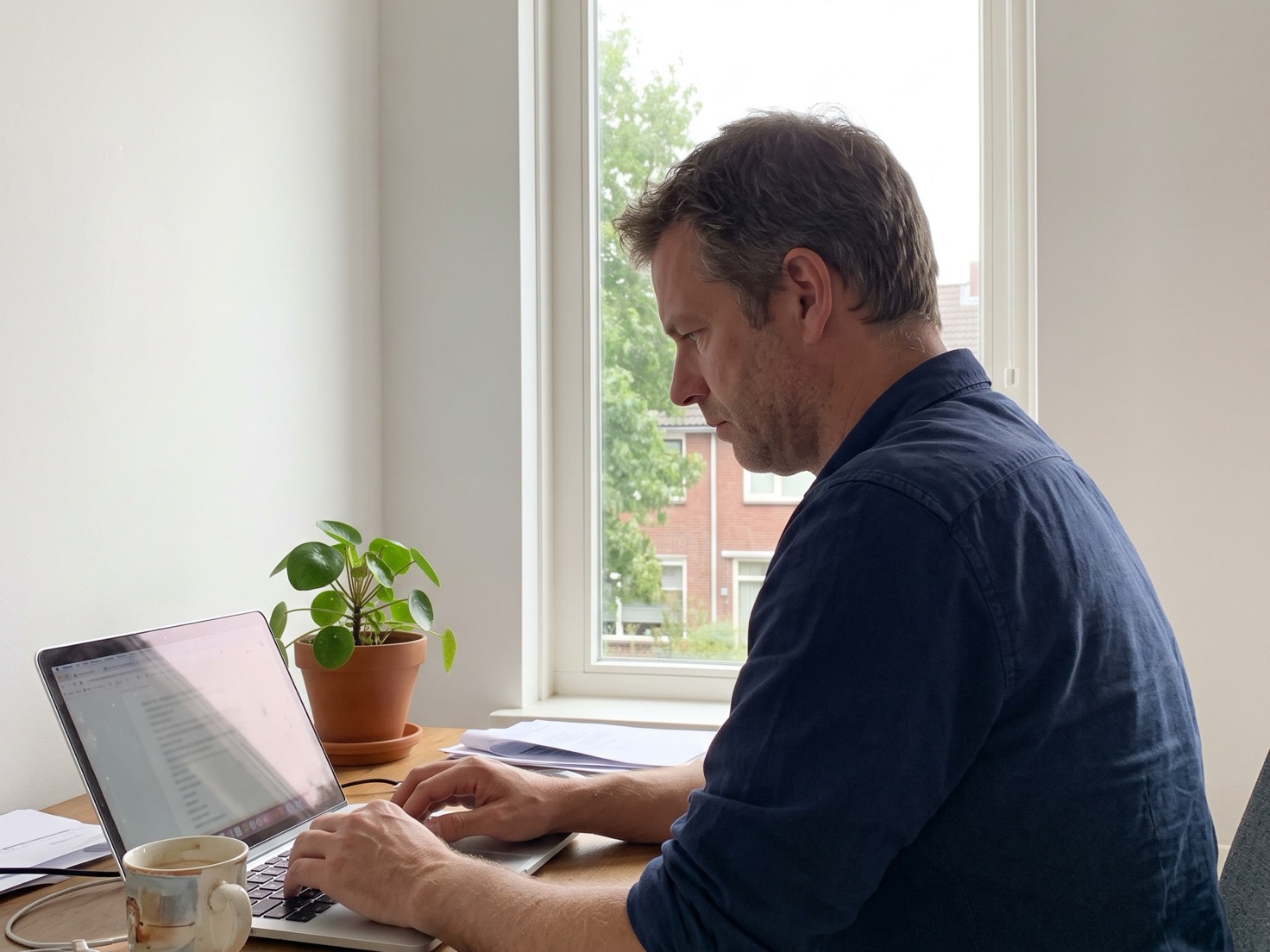 Man werkt thuis aan zijn laptop en bekijkt een oud document op zijn scherm