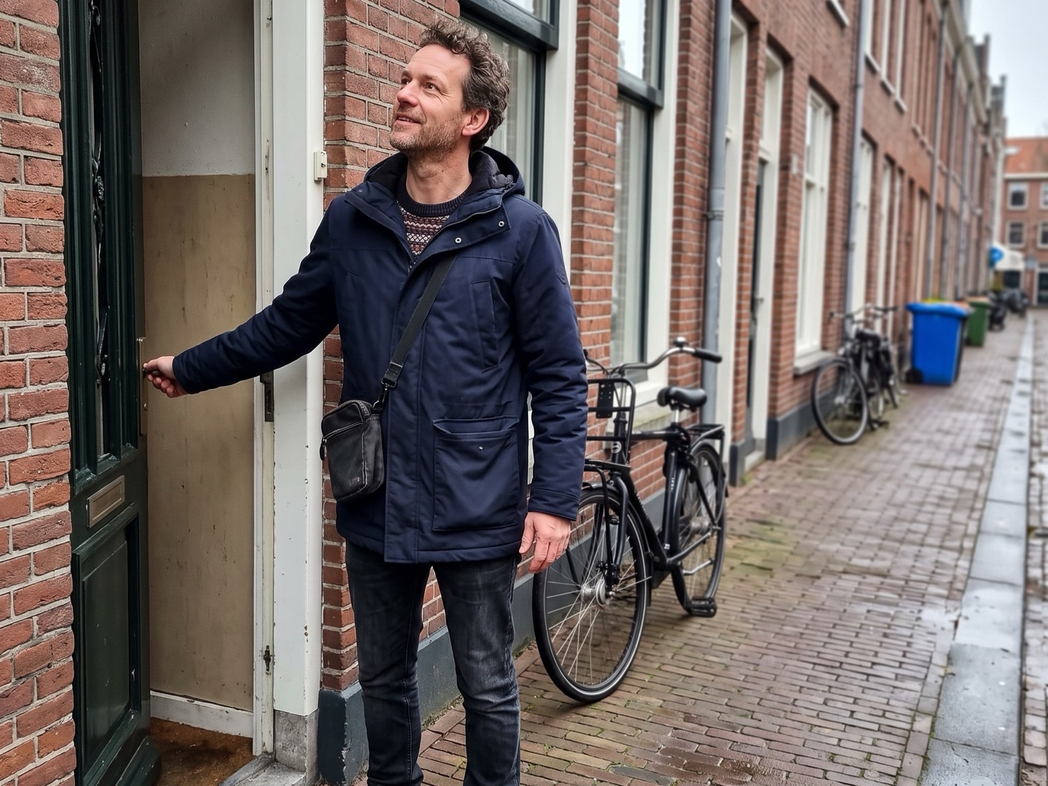 Ondernemer staat op de stoep voor zijn pand na een werkdag