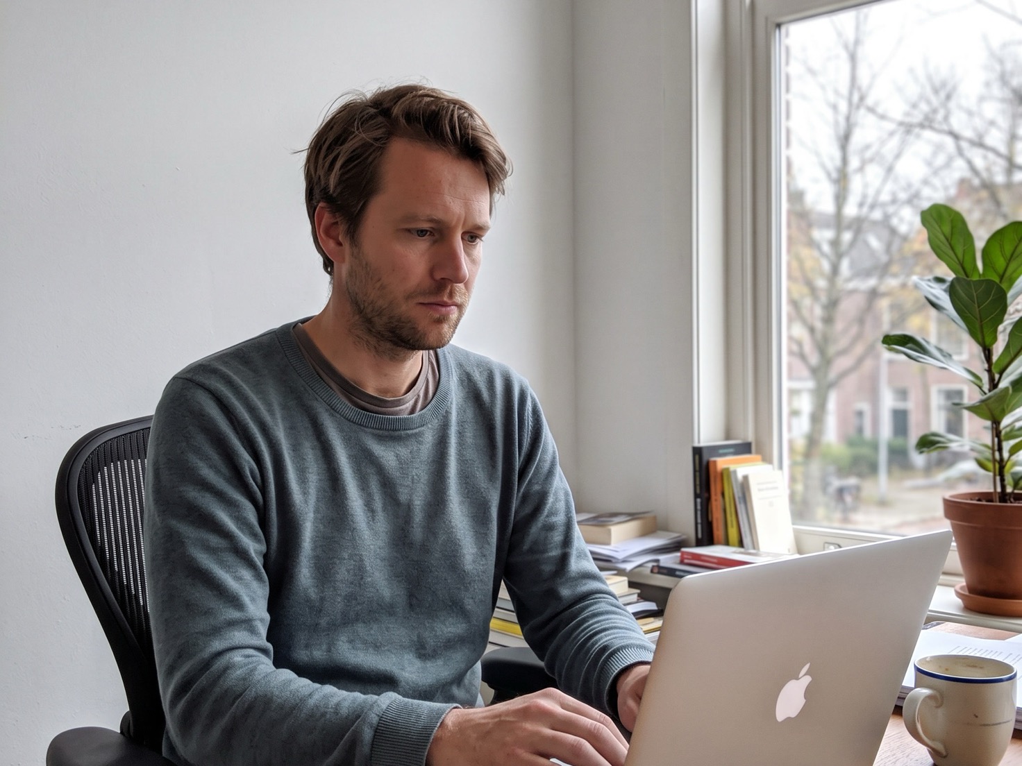 Zelfstandig ondernemer twijfelt achter zijn laptop of hij op een LinkedIn-bericht moet reageren