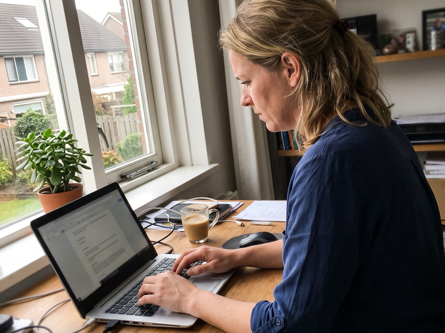 Vrouw werkt geconcentreerd aan haar laptop in haar thuiskantoor
