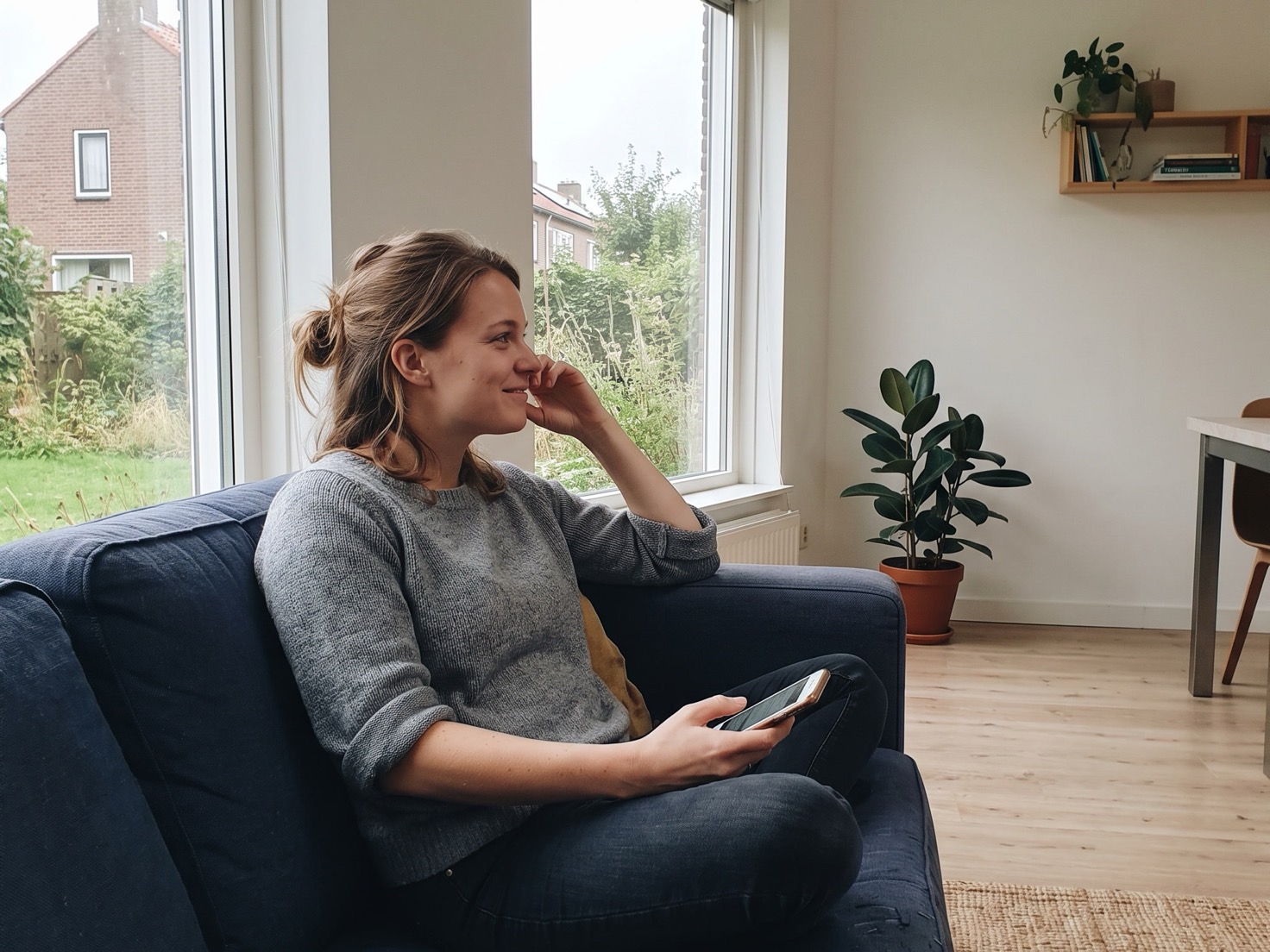 Vrouw op de bank met haar telefoon in de hand die haar LinkedIn-profiel bekijkt