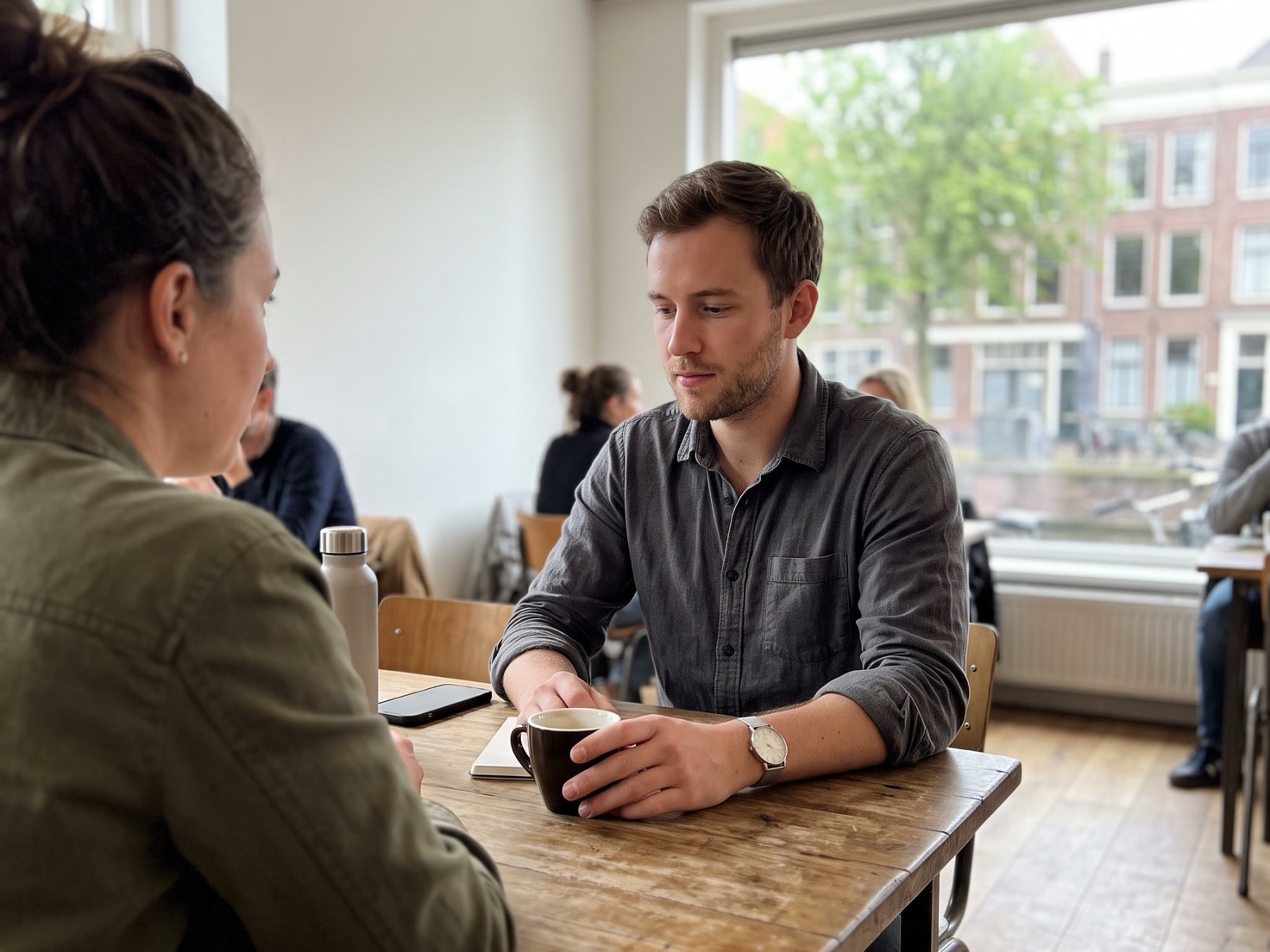 Man luistert rustig aan tafel tijdens een gesprek in een lichte woonkamer