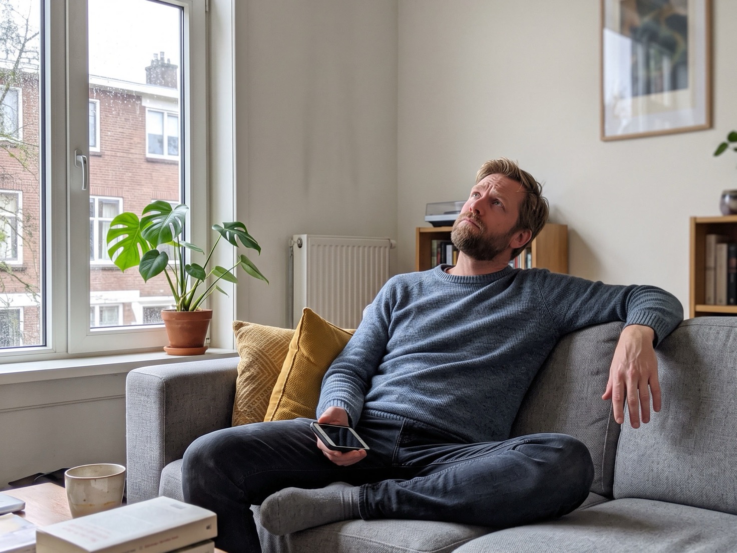 Ondernemer op de bank met zijn telefoon, denkend over de aankondiging van zijn workshop