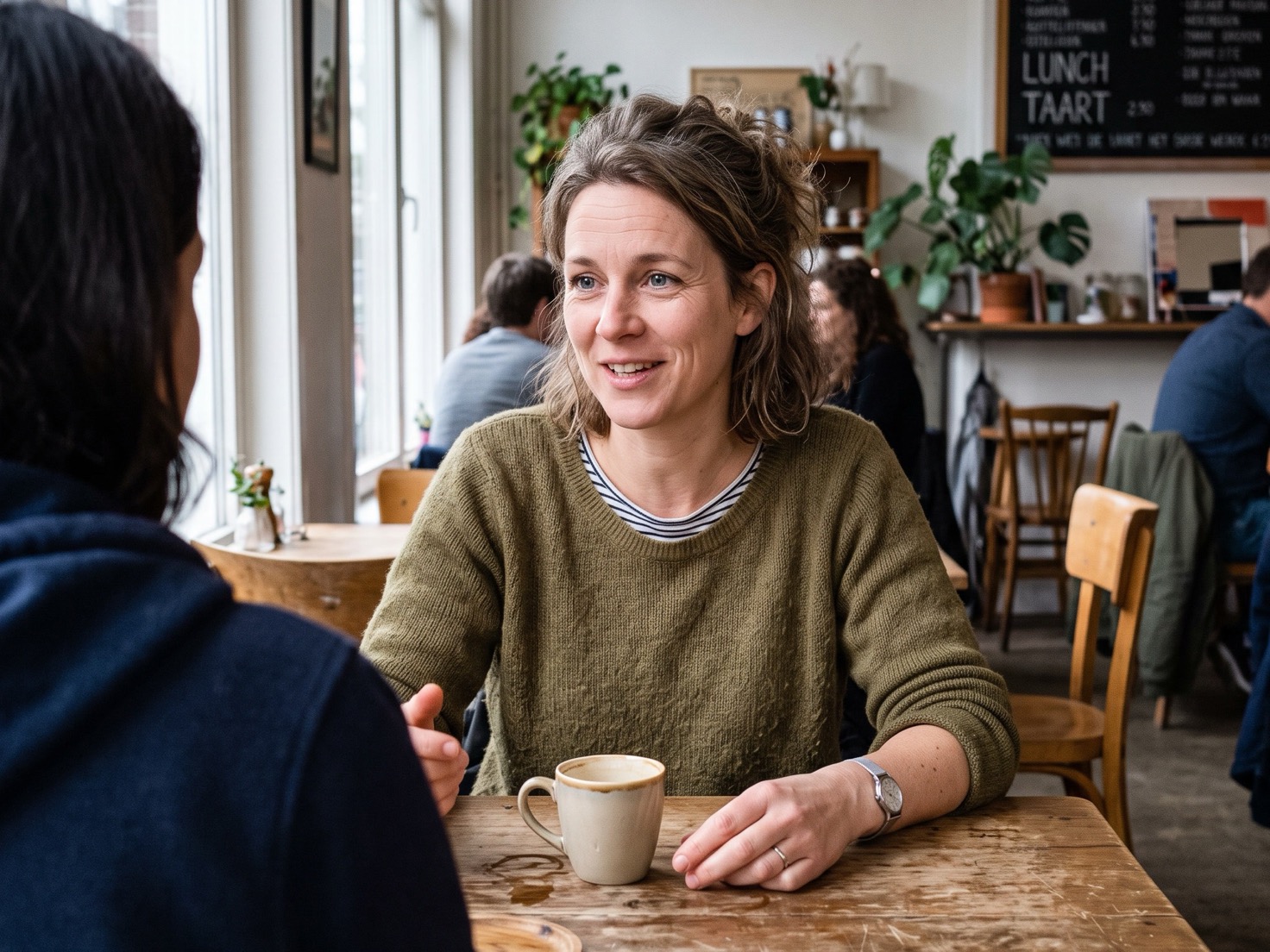 Vrouw in gesprek aan een tafel, symbool voor zichtbaar blijven bij klanten zonder dagelijks te posten